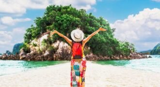 Happy traveler raising arms on island beach, showcasing travel money tips UAE for budget-friendly vacations