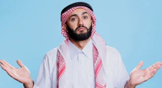 Confused Middle Eastern man in traditional keffiyeh and white kandura shrugging with hands raised, expressing uncertainty about credit card decisions or financial mistakes in the UAE