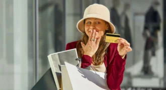 Woman shopping at a mall holding a credit card and shopping bags, illustrating consumption creep and lifestyle spending in the UAE.