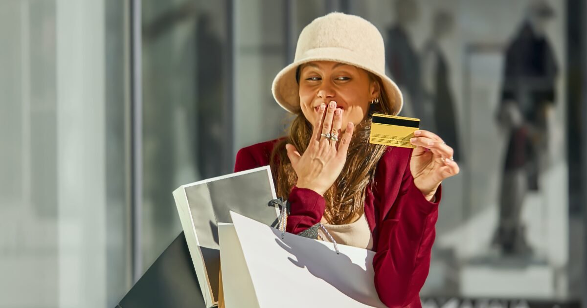 Woman shopping at a mall holding a credit card and shopping bags, illustrating consumption creep and lifestyle spending in the UAE.
